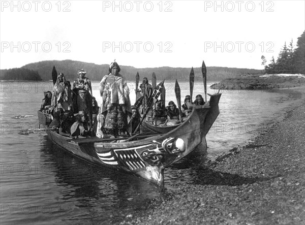 Edward S. Curits Native American Indians - Two canoes pulled ashore with wedding party, bride and groom standing on 'bride's seat' in the stern circa 1914.
