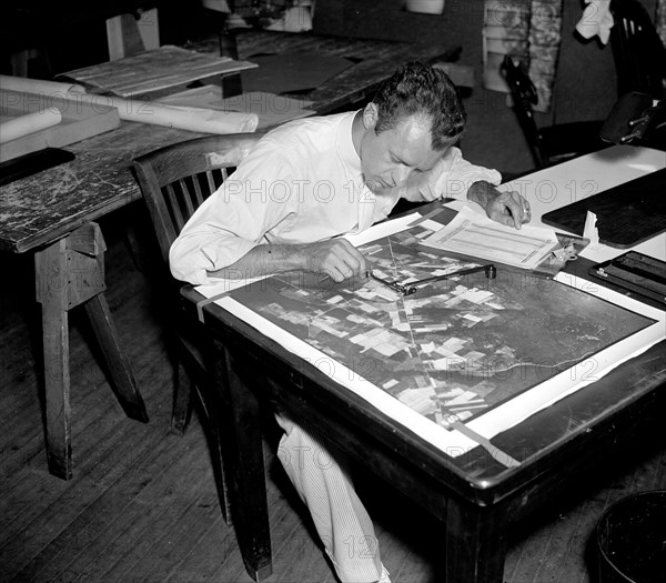 A worker using a planimetor, which measures the exact acreage in each section of land surface photographed circa 1937.