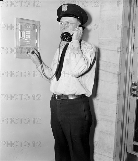 F.B.I. guard reports in. Washington, D.C., Aug 4. Officer Ray D. Buckingham using a plug-in telephone, which every guard carries as part of his regular equipment circa 1937.