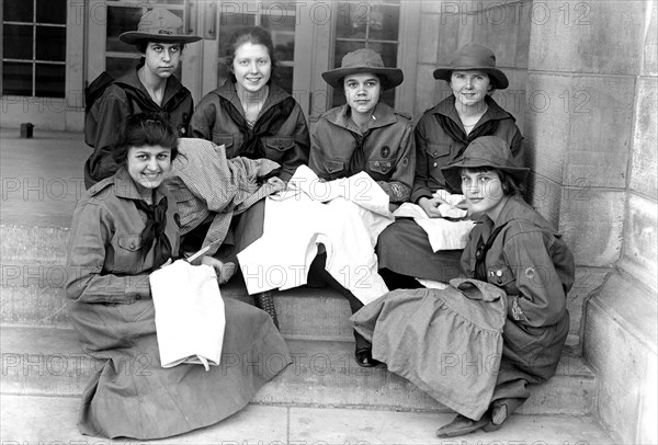 Girl Scouts sitting down and sewing circa 1918.