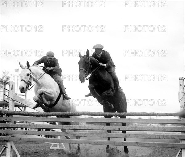 Horses jumping over rails in race circa 1919 .