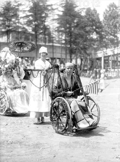 Wounded WW I soldiers at Walter Reed Hospital participate in a 4th of July wheel chair parade circa 1919 .