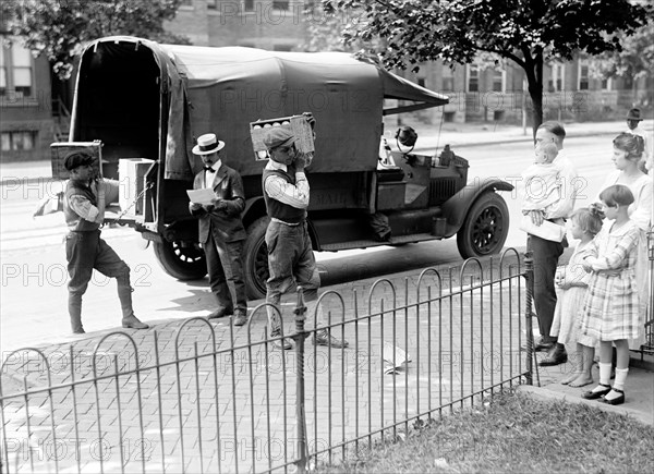 Men carrying boxes of mail (possibly canned tomatoes) to a home circa 1919.