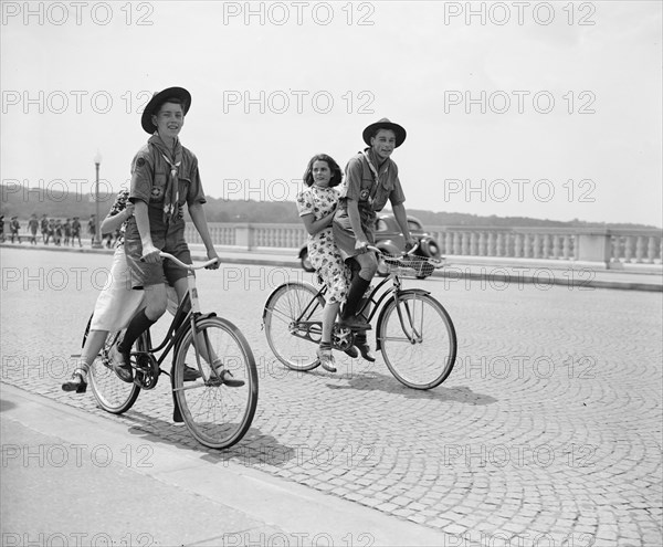 Two Boy Scouts giving their girlfriends a ride on their bicycles across the Arlington Bridge circa 1937.