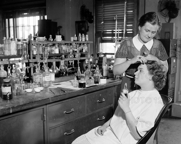 Testing cosmetics for the government. Washington D.C. July 10- Mrs. R. Goodman, is shown sitting with Mrs. C.R. West applying dye for the hair, some dyes contain lead and the poison in the dye may lead to chronic poisoning circa 1937.
