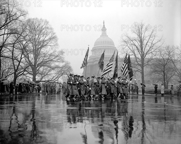 Thousands braved a heavy rain today to witness the Army Day parade pass the U.S. Capitol - here, soldiers present the colors, the flags, to parade watchers circa 1939.