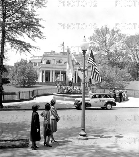 May 4, 1939 - Some visitors to Washington looking at flags of the United States and Nicaragua which decorate each lamp post along the line of the parade for the Nicaraguan President Somoza.