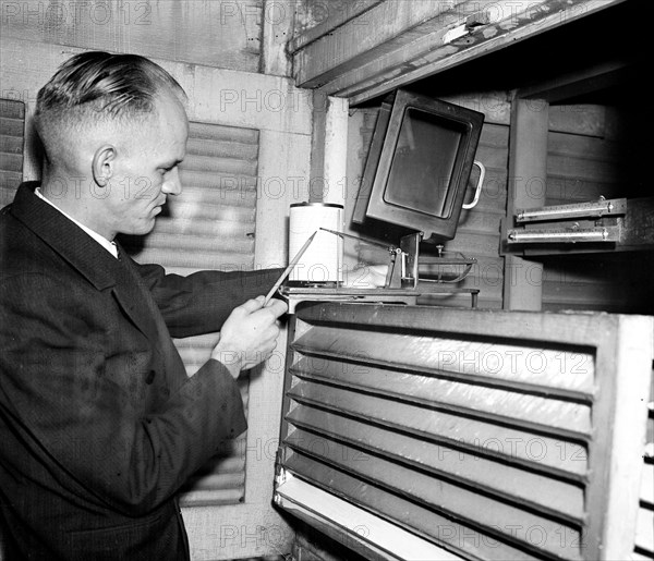 Weather employee at typical weather station with a temperature chart circa 1936.