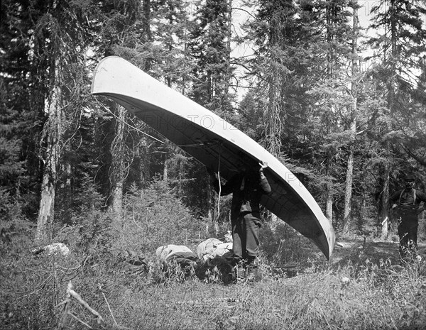 Long Portage (1 2/3 miles into Stillwater Lake)' Man carrying a canoe circa 1909.