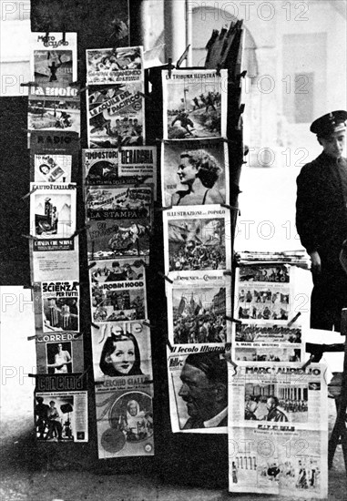 News stand on street corner in Bologna Italy filled with newspapers and magazines for sale circa late 1930s .