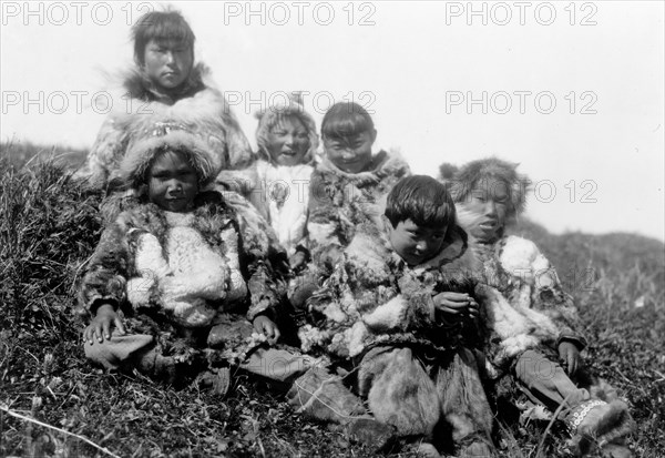 Edward S. Curits Native American Indians - Photograph shows six Nunivak children dressed in fur, sitting on hill circa 1929 .