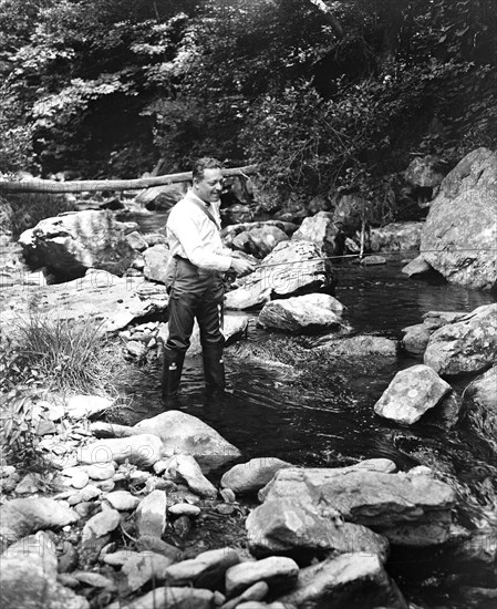 A man fishing in a river circa 1932.