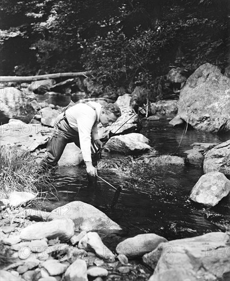 A man fishing in a river circa 1932.