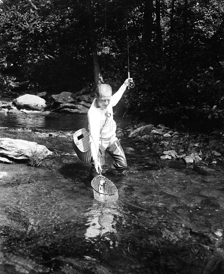 A man fishing in a river circa 1932.