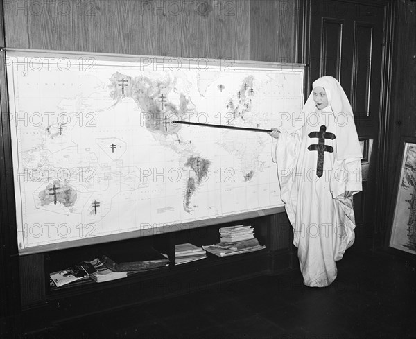 Miss Mildred Showalter of Washington, dressed as the Spirit of the Double-barred cross of the anti- tuberculosis movement throughout the world, points to various battlefronts throughout the world where the fight is being carried on against the 'White Plague.' circa 11/25/1935.