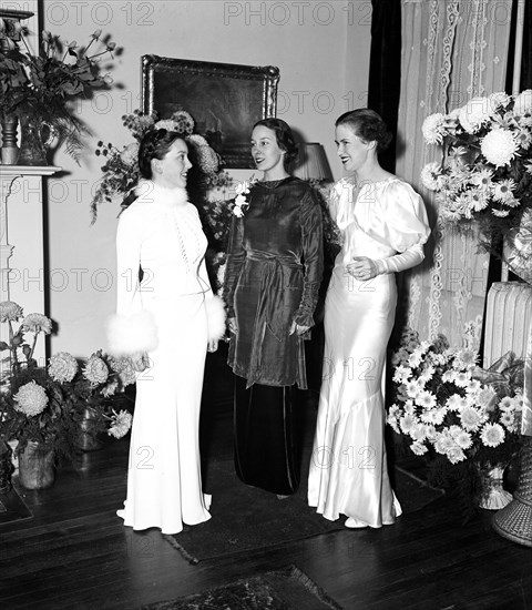 Women wearing elegant evening gowns circa 1934.