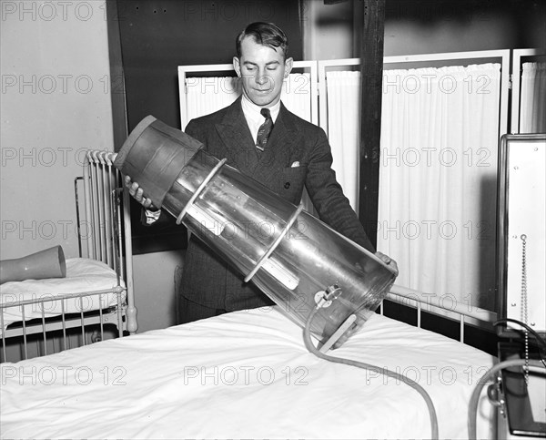 Leg saver. Chester Antos, student at Georgetown University medical school, photographed with the newly devised Emerson suction pressure apparatus which designers believe will prevent amputation in many cases circa 11/12/1935.