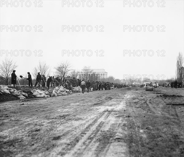 Men filling sandbags and placing them to protect an area of Washington D.C. during flooding of the  Potomac River, Washington, D.C. circa March 19, 1936 .