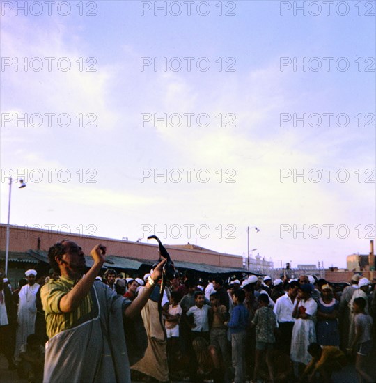 Snake charmer holding a snake in the marketplace in Marrakesh Morocco circa 1969.