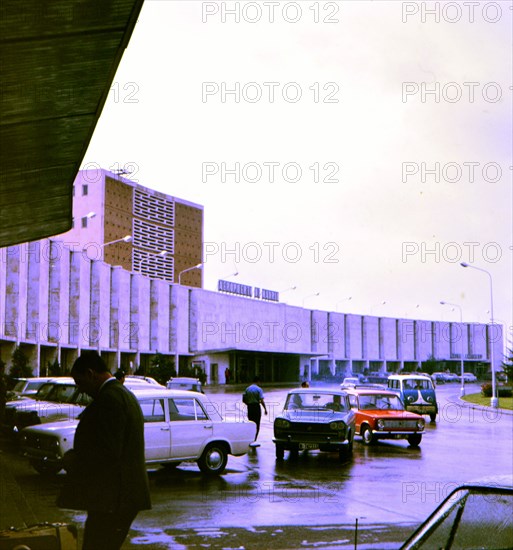 Cars driving dropping off passengers at an airport terminal in Madrid Spain circa 1969.