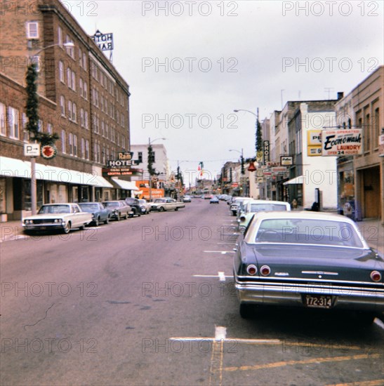 Parked cars on a city street in Portage, WI in late 1966, Ram Hotel on the left  (Christmas decorations on lamps) .