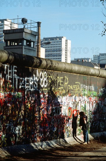 A West German child attempts to chip off a piece of the Berlin Wall as a souvenir.   .