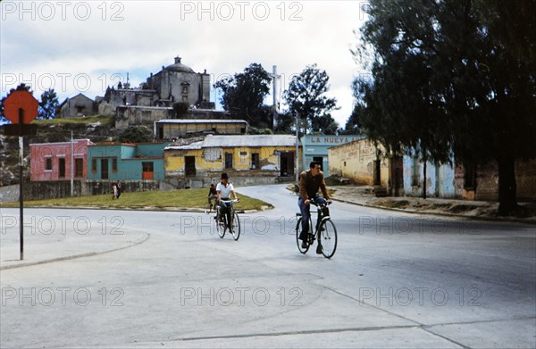 1962 Guatemala - Street scene, people riding bicycles in a Guatemala village in the early 1960s.