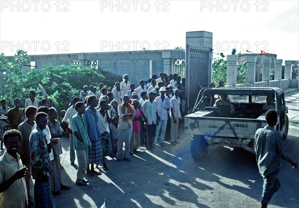 1992 - Somalis watch as an M-998 series vehicle enters the Joint Task Force Somalia headquarters.