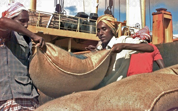 Somali workers unload a ship carrying sacks of wheat