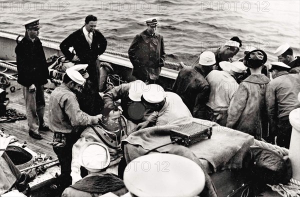 USS Falcon crewmen suit up two Navy divers