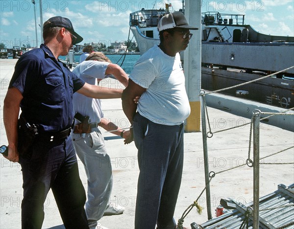 Member of a Coast Guard boarding team places a man under arrest