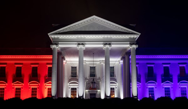The White House North Portico is lit in red-white and blue lights
