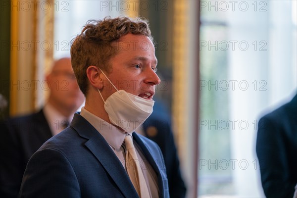 A reporter removes his mask to ask a question