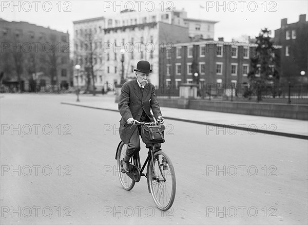 Old man riding his bicycle to work on a city street