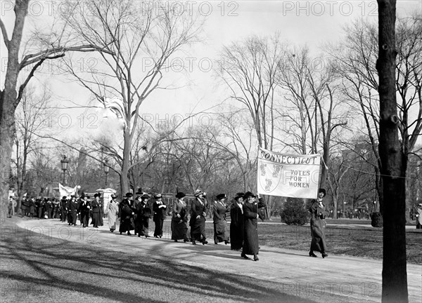 Woman suffragettes marching to the White House holding banners