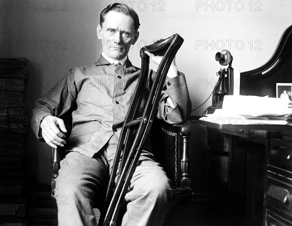 Man with crutches seated at desk