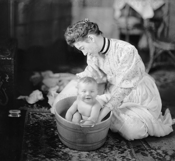 A mother giving her baby a bath in the early 1900s.