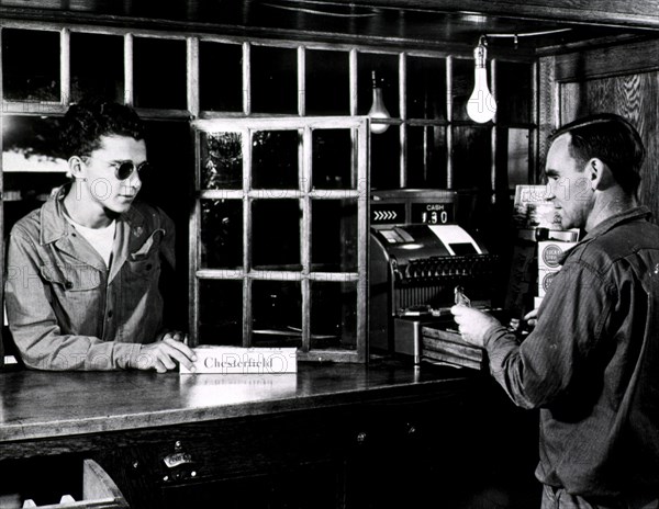 A visually impaired man purchasing a box of cigarettes at a store counter