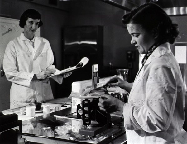 Two female dietitians weigh and measure foods before they are served to patients of restrictive diets.