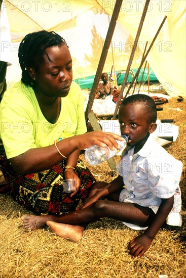 A mother gives her child water at the Kitali refugee camp