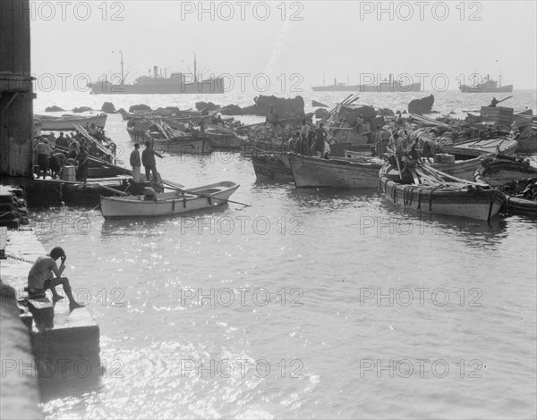 Construction of Jaffa pier. Lighters on the Jaffa coast inside the so called Rocks of Andromeda, men in boats in the harbor ca. 1934