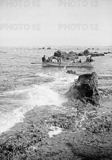 Men in a boat passing the rocks near Jaffa/Joppa ca. 1900