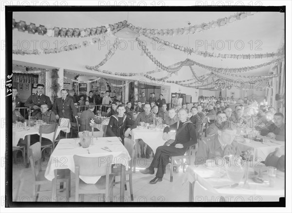 Christmas decorations in the YMCA hostel dining hall, military personel sitting at tables Dec. 1943