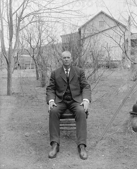 Man sitting in a chair outdoors ca. between 1910 and 1935