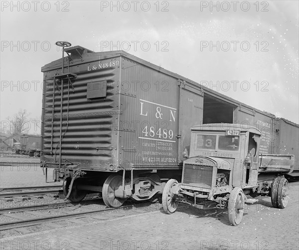 Truck parked next to an empty railroad car (box car) ca.  between 1910 and 1926