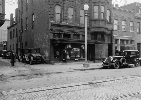 Man walking outside Tom's Lunch & Delicatessen shop ca. between 1910 and 1935