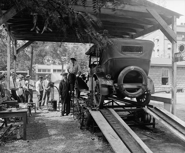 Car on a rack at the Havoline Oil Company, men standing around waiting ca.  between 1910 and 1935