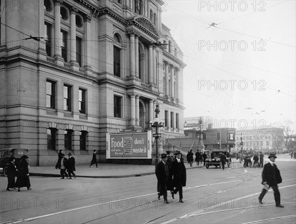 Pedestrians walk by a Food Don't Waste it Billboard donated by Old Colony Advertising Company ca.  between 1910 and 1935