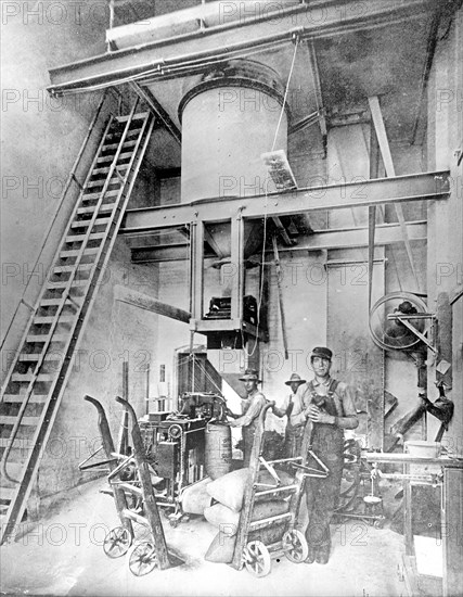 Workers filling, weighing, and sewing sacks of granulated sugar in a beet sugar factory ca.  between 1910 and 1920