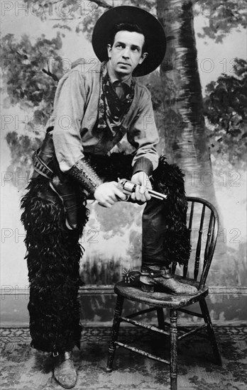 Stanley James, man posing dressed as cowboy with a pistol, ca. between 1909 and 1919